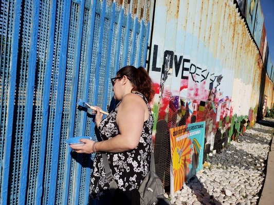 Lisa Votino-Tarrant painting an area of the border wall in Tijuana