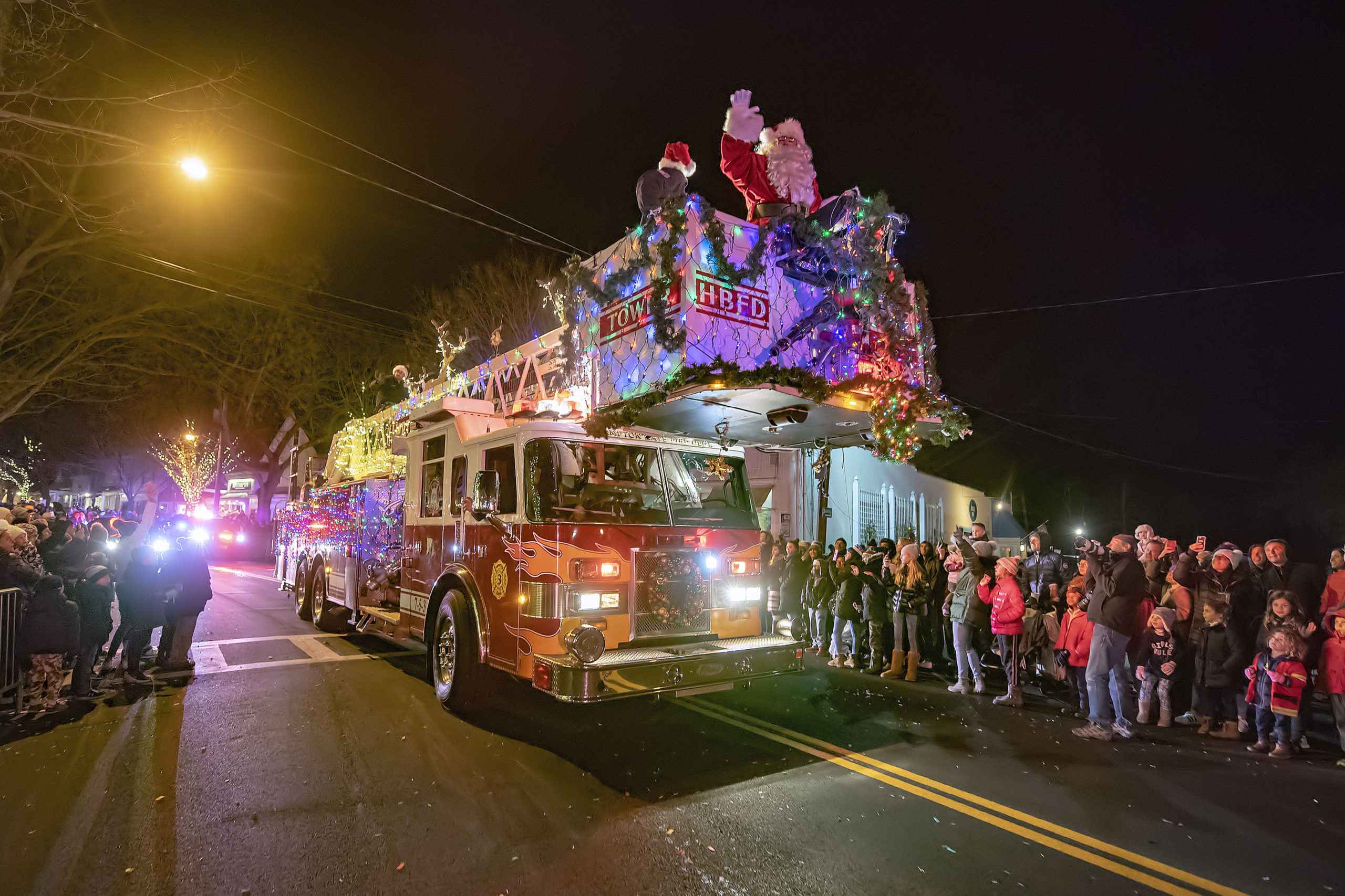 Santa Claus arrives on the parade route atop a Hampton Bays Fire Department tower ladder truck during the 2019 