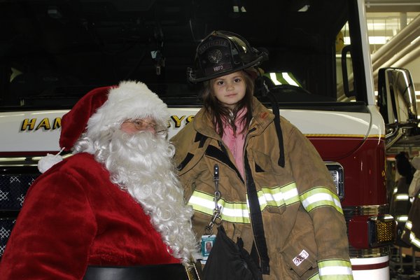 Bill John Koehler as Santa poses with Cecilia Bellucci at the Hampton Bays Fire Department. KATE RIGA