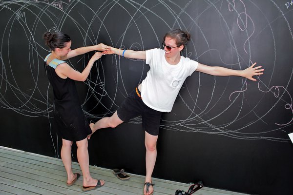 Marie De Testa tracing Annick Lavallee-Benny on the chalkboard wall.