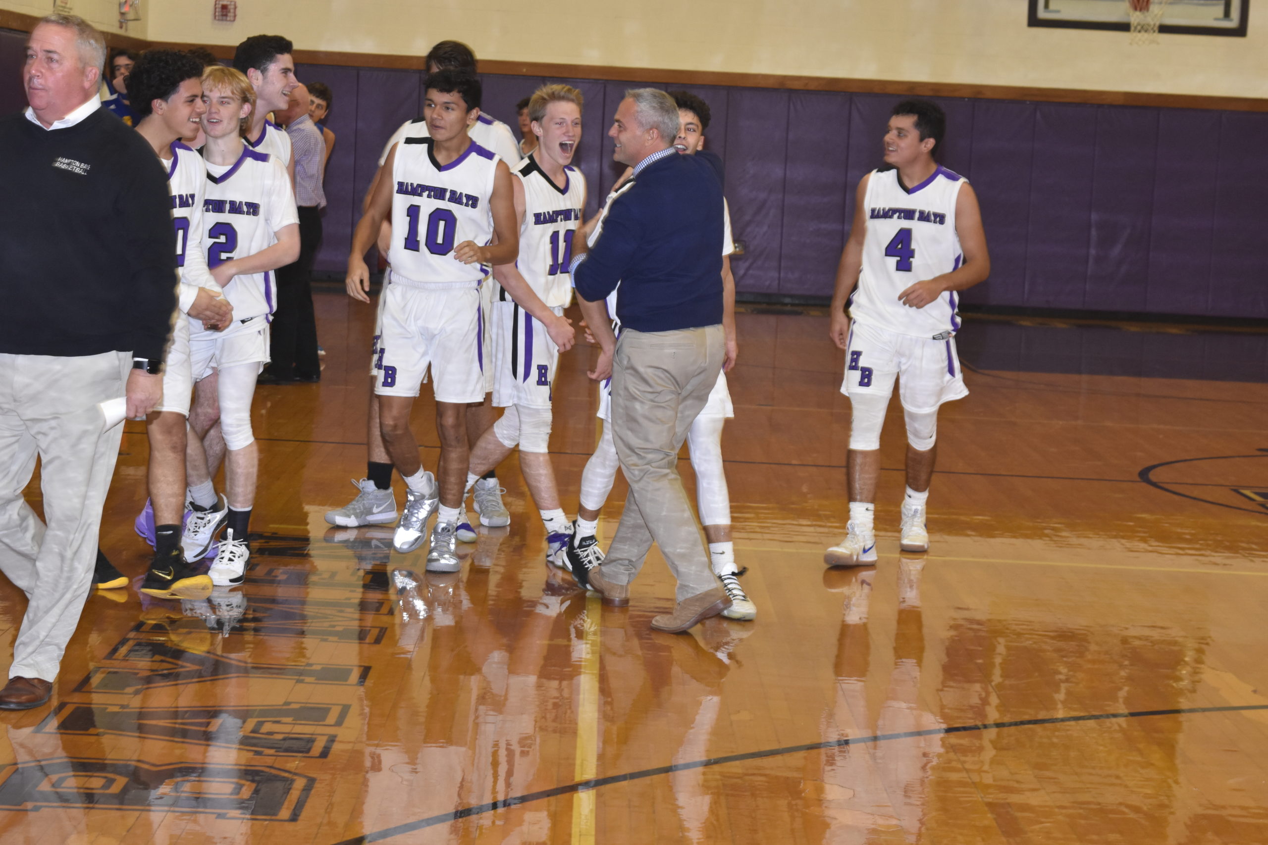 Assistant coach John Paga and teammates congratulate Steven Mora after his half-court buzzer beater led to a 54-51 victory over West Islip on Friday night.