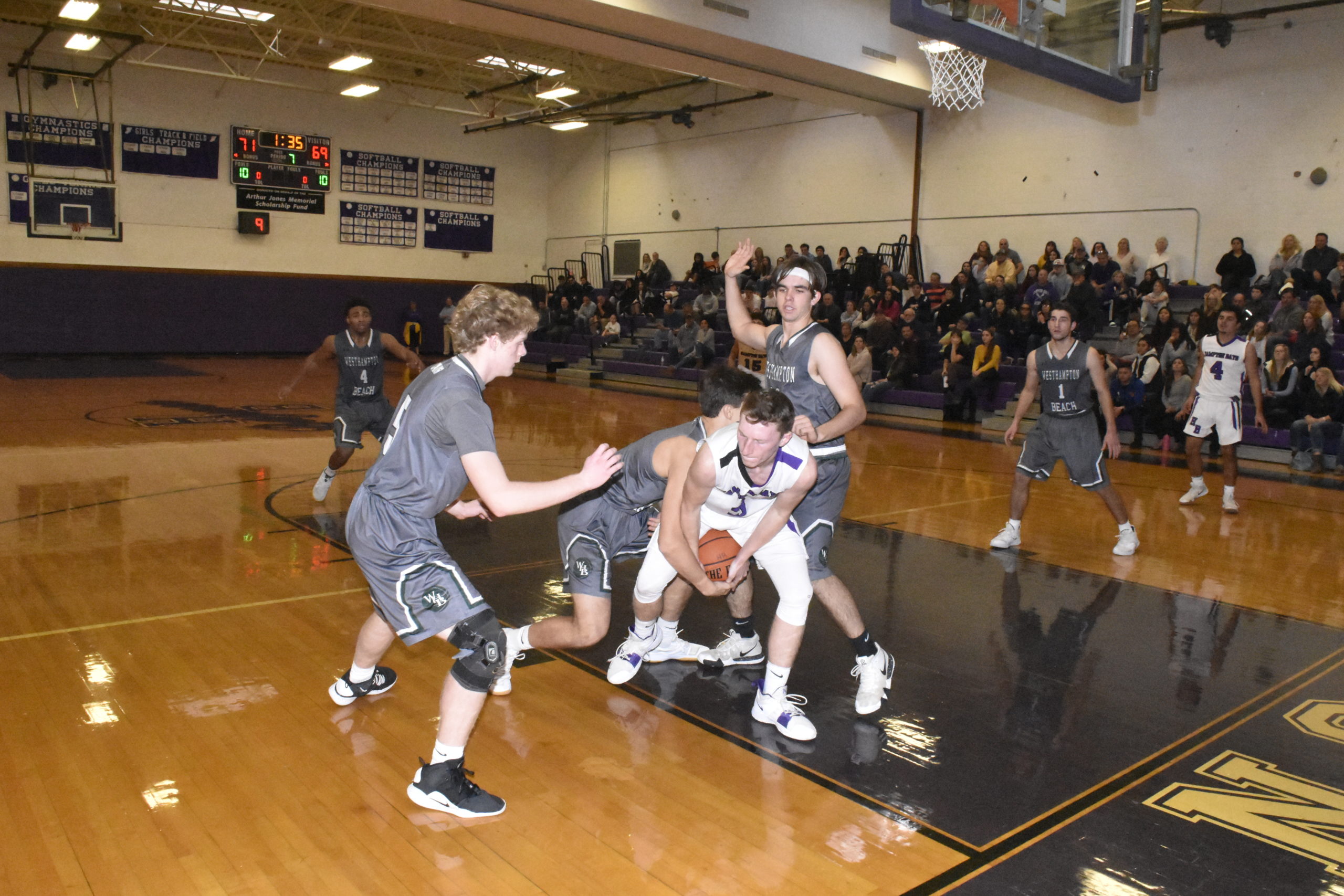 Hampton Bays senior Aaron Butters tries to hold on to the ball as a trio of Hurricanes surround him.
