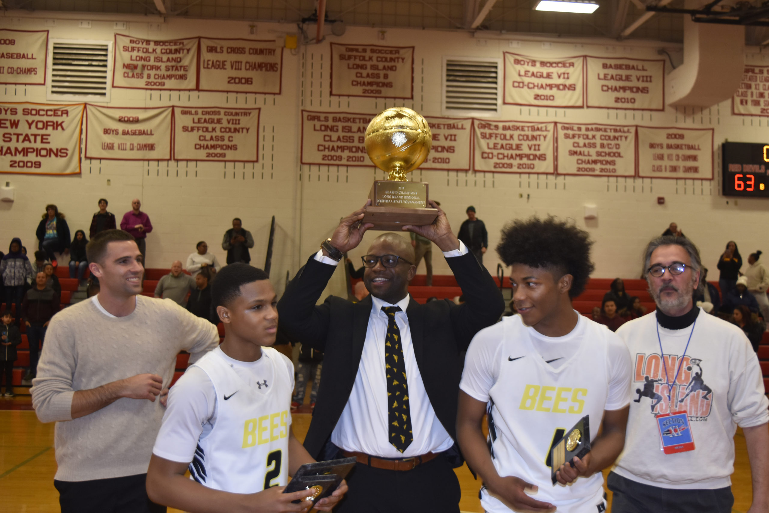 Bee Win First L.I. Title 
March 7 -- The Bridgehampton boys basketball team defeated Academy Charter for its first ever Long Island Class D Championship. Head coach Ron White hoists the trophy.