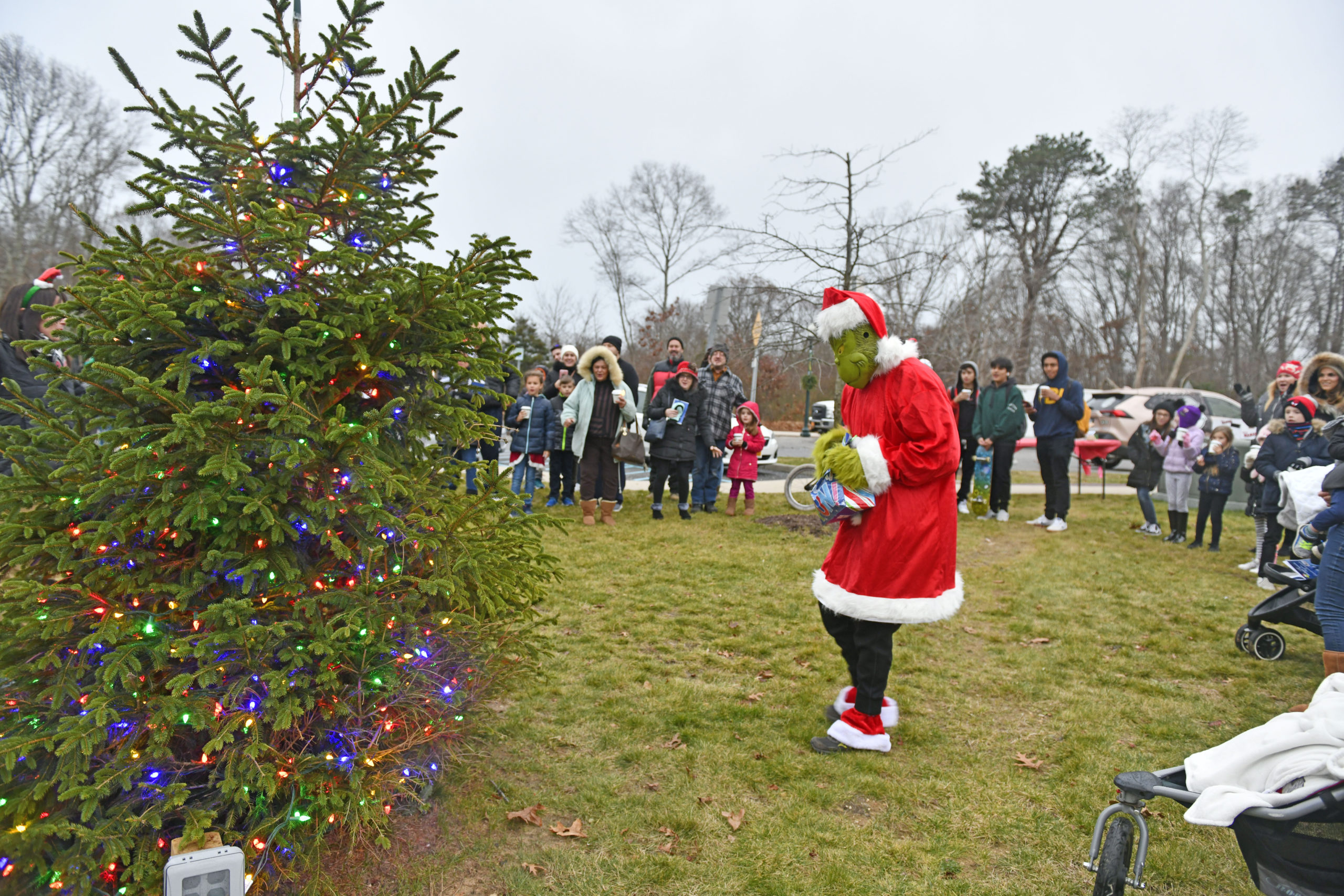 Festivities were cut short due to the rain but that didn't stop the Grinch, the Dickens Carolers and visitors from singing a quick carol and lighting the tree at Good Ground park in Hampton Bays on Friday.  DANA SHAW