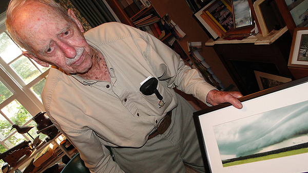 Richard Hendrickson shows a photograph of an unusual cloud over Bridgehampton. Some of his guns are displayed in the background. COLLEEN REYNOLDS