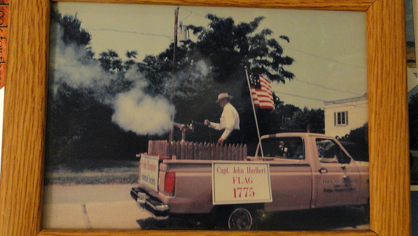A photograph of a photo in which a younger Richard Hendrickson is blasting a cannon. 
