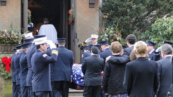 Southampton Fire Department members stand in salute Saturday morning as Bill Frankenbach's flag-draped casket is led into St. John's Episcopal Church in Southampton Village. Mr. Frankenbach's family follows. COLLEEN REYNOLDS
