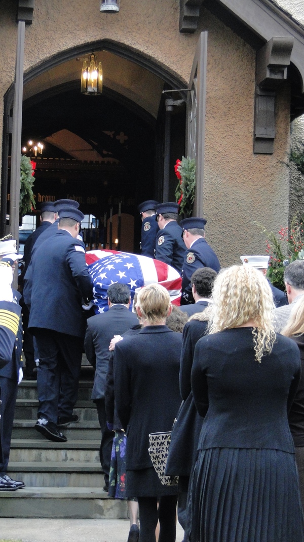 Bill Frankenbach's flag-draped casket is carried into St. John's Episcopal Church in Southampton Village Saturday morning. His relatives follow. COLLEEN REYNOLDS
