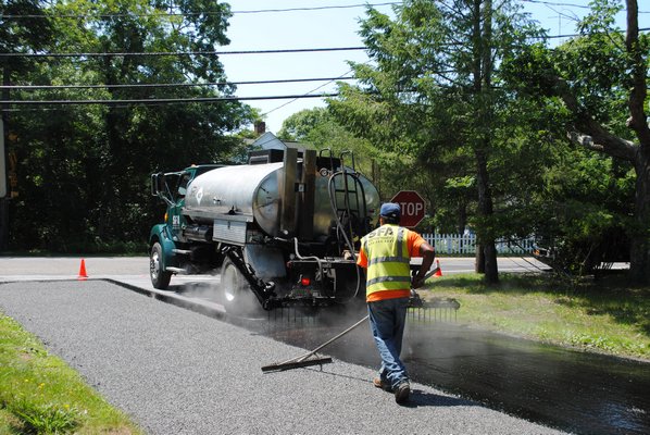 Consruction workers are putting oil and stone down on Foster Street in Quogue. AMANDA BERNOCCO