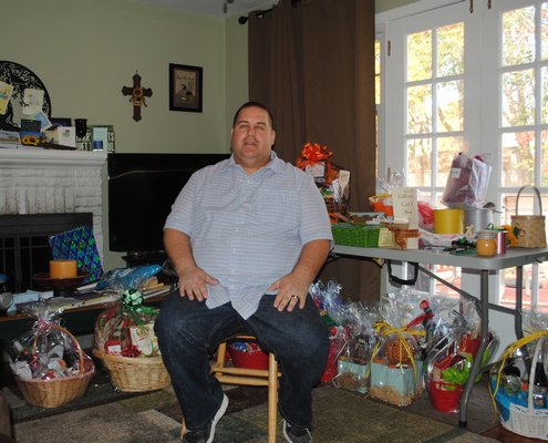 David Kohler sits in his living room among the gifts donated to be auctioned off at his fundraiser. AMANDA BERNOCCO