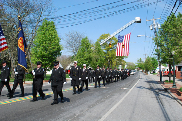 Firefighters pay tribute to Benjamin W. Lupia as his funeral procession passes the Hampton Bays firehouse on Saturday afternoon.  <br>Photo by Will James