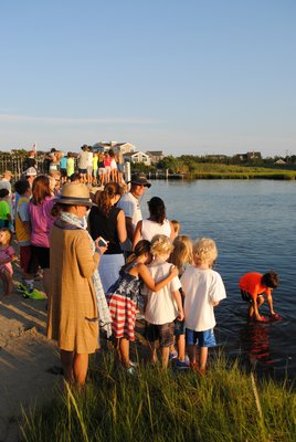 Families line up around the bay to watch the rubber ducks cross the finish line at the Quogue Association Duck Race. AMANDA BERNOCCO