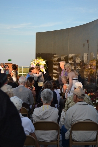 Family members embrace in front of the names of those lost at the 15th anniversary ceremony of the Flight 800 crash on Sunday night. LAURA COOPER