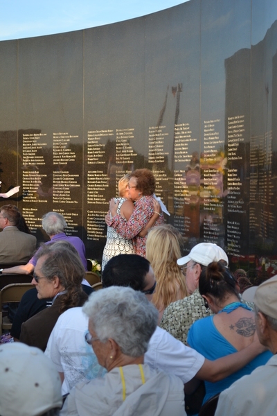 Family members embrace in front of the names of those lost at the 15th anniversary ceremony of the Flight 800 crash on Sunday night. LAURA COOPER