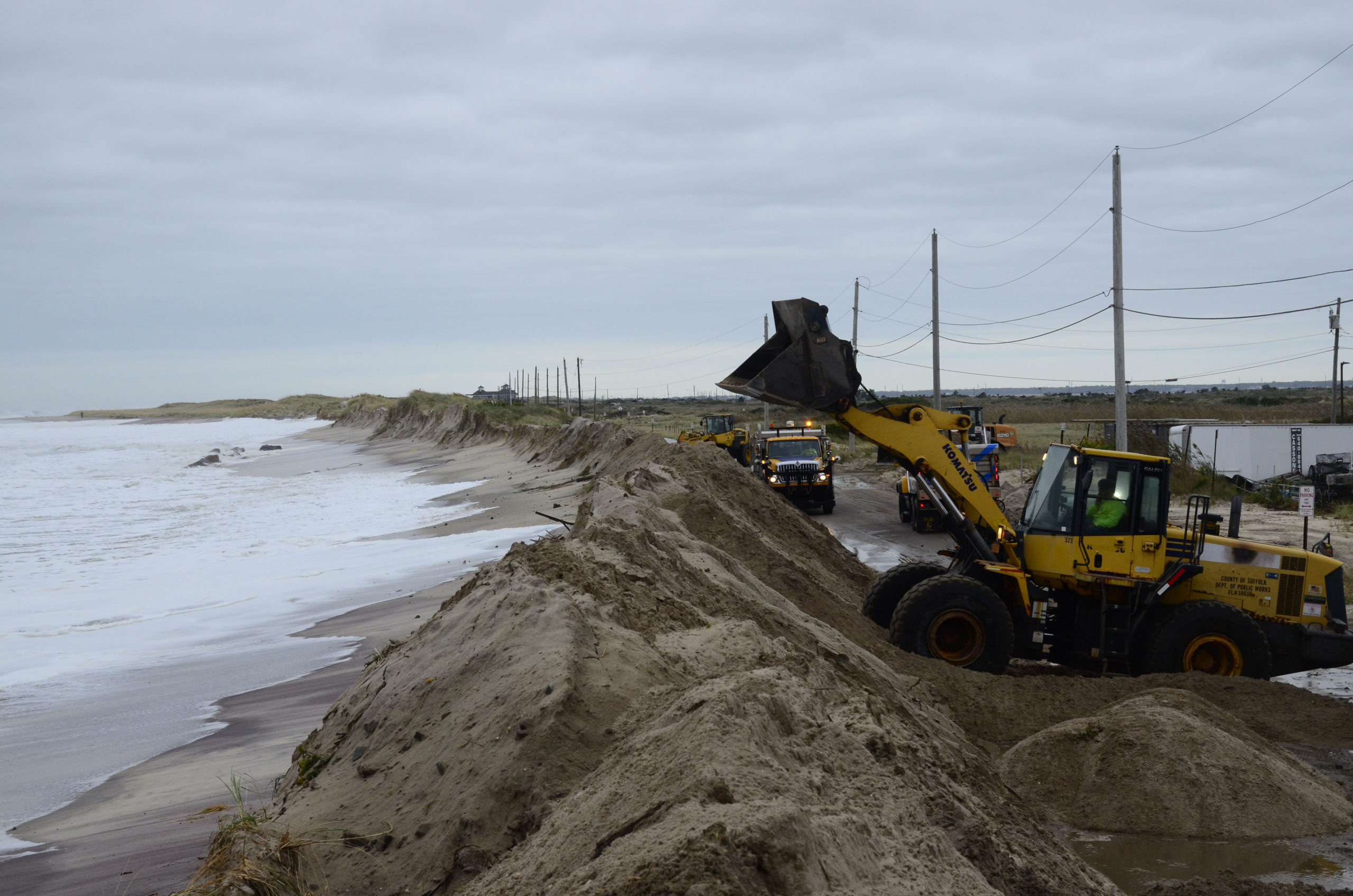 Quick Action Closes Dune Breach 
October 17 -- Big surf and strong winds from a nor’easter churning in the Atlantic Ocean caused a section of Dune Road near the Shinnecock Commercial Fishing Docks to experience washovers on Thursday night, October 10, prompting local, county and state agencies to pounce into action to bolster the dunes. The washovers were the result of a nearly 100-yard section of dune eroding away with the surf and tides, which were higher than normal during the storm. Last Thursday, Southampton Town Supervisor Jay Schneiderman declared a state of emergency due to severe erosion and the potential of coastal flooding along the eastern end of Dune Road, in anticipation of the nor’easter. The declaration allowed the town to accelerate any required coordination with the State Department of Environmental Conservation to move sand and rebuild the dune. It also allowed the town to request assistance from the Suffolk County Department of Public Works to bring in heavy equipment to reconstruct the dune.