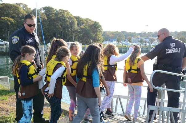Town of Southampton Bay Constable Rich Franks helps Brownie Troop 759 member Makayla Vignieri put on her life jacket at the Meschutt marina on October 21. GREG WEHNER