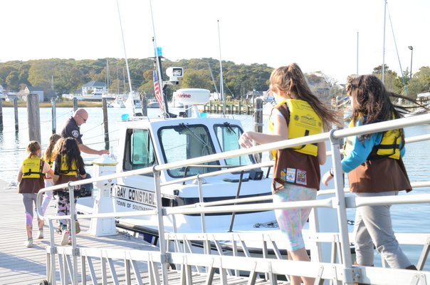 Southampton Bay Constables Donnie Downs (left) and Rich Franks (right) walk members of the Quogue Brownie Troop 759 down a ramp to the dock at Meschutt marina