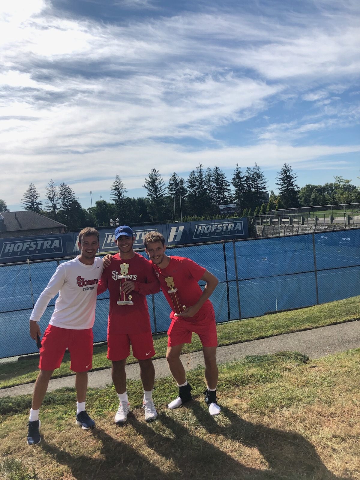 Dillon Pottish, standing directly behind the Big East sign with the Big East Championship trophy, along with Richard Sipala, standing to Pottish's right, helped lead the St. John's men's tennis team this past season as head and assistant coaches.