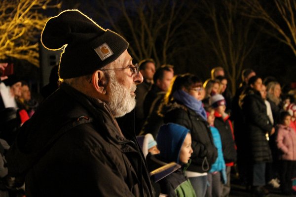 East Quogue Civic Association President Al Algiei watches the East Quogue Elementary School Senior Choir perform during the annual Christmas tree lighting Saturday night in the East Quogue Village Green park. KYLE CAMPBELL