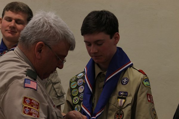 Scoutmaster Allen Schneider helps Johann Tran put on his Eagle Scout neckercheif on January 11 at the St. Rosalie's Community Center on Montauk Highway in Hampton Bays. KYLE CAMPBELL