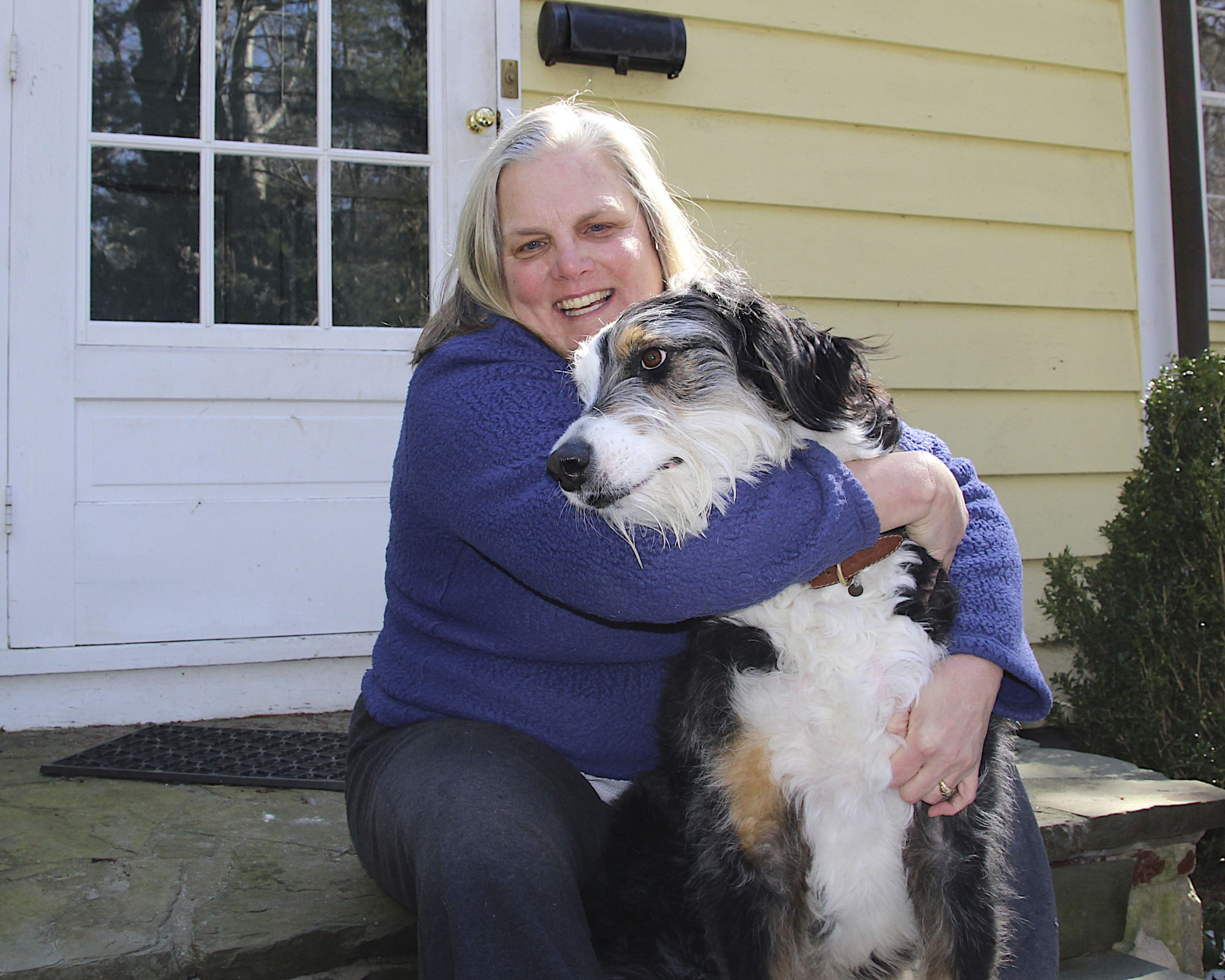 Lori Marsden in front of her home on Saddle Lane with one of the dogs she babysits