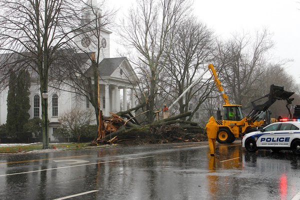 Crews work to clear a large tree that snapped and fell across Main Street in East Hampton Village near the Presbyterian Church on Tuesday. The blizzard spared the East End but high winds and rain pounded the area.