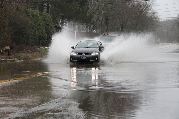 Motorists drive through water along Three Mile Harbor Road on Tuesday afternoon.  KYRIL BROMLEY