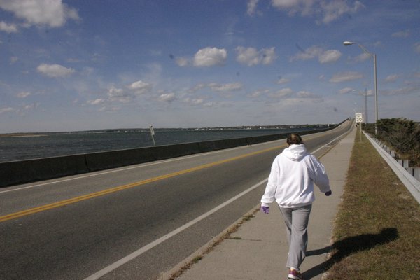 Anna Tuzzolo walks across the Ponquogue Bridge in Hampton Bays on a chilly October morning. KYLE CAMPBELL