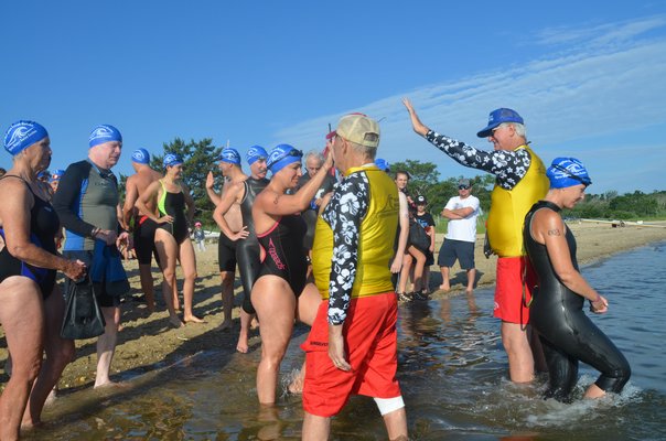 Swimmers in the half-mile head out to the start. Each is counted before entering the water.