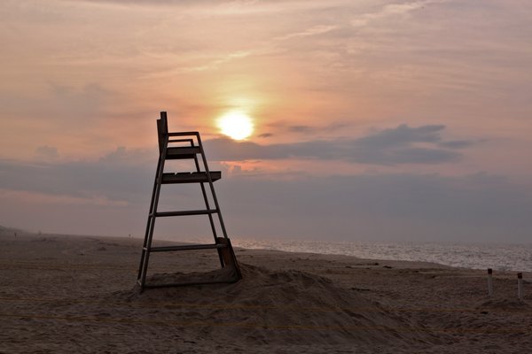 The sun slowly makes its way from behind an empty lifeguard stand at Rogers Beach in Westhampton Beach last Thursday morning. NEIL SALVAGGIO