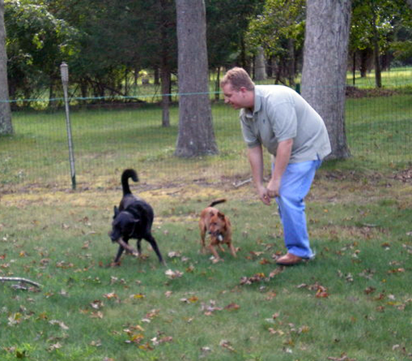 The Reverend Anthony Larson plays with his dog in the backyard of his Springs home.