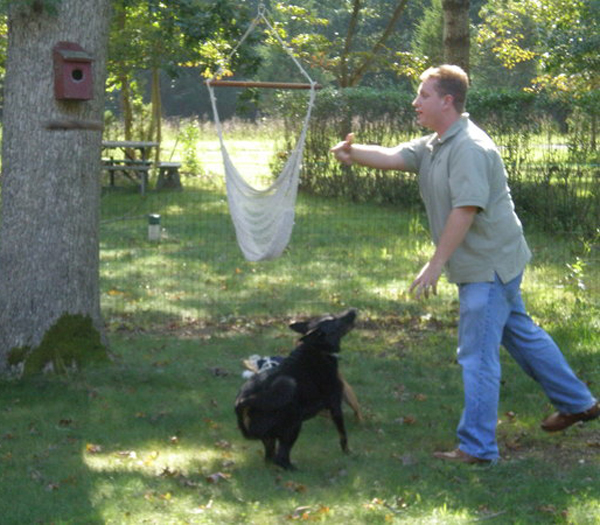 The Reverend Anthony Larson plays with his dogs in the backyard of his Springs home.