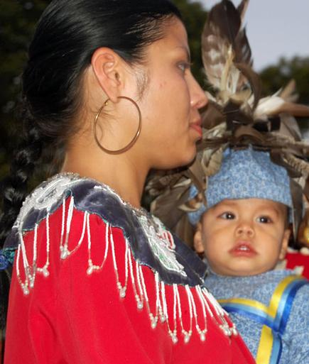 A Native Amercian Dancer holds her child during the Grand Entry. BRIAN BOSSETTA
