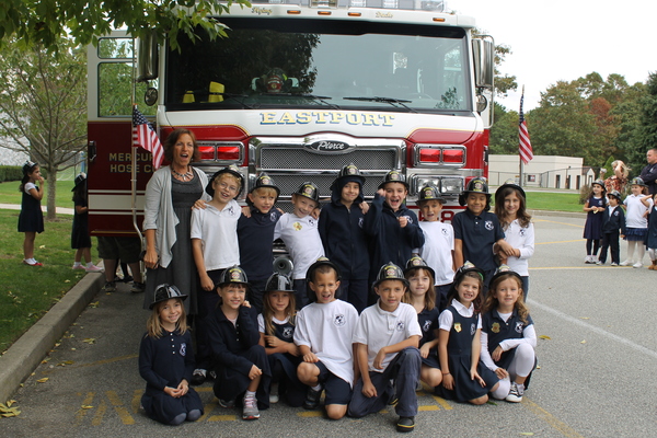 Second-grade students from Mrs. C's class at Raynor Country Day School pose with firefighters in front of the Eastport Fire Department Truck.
