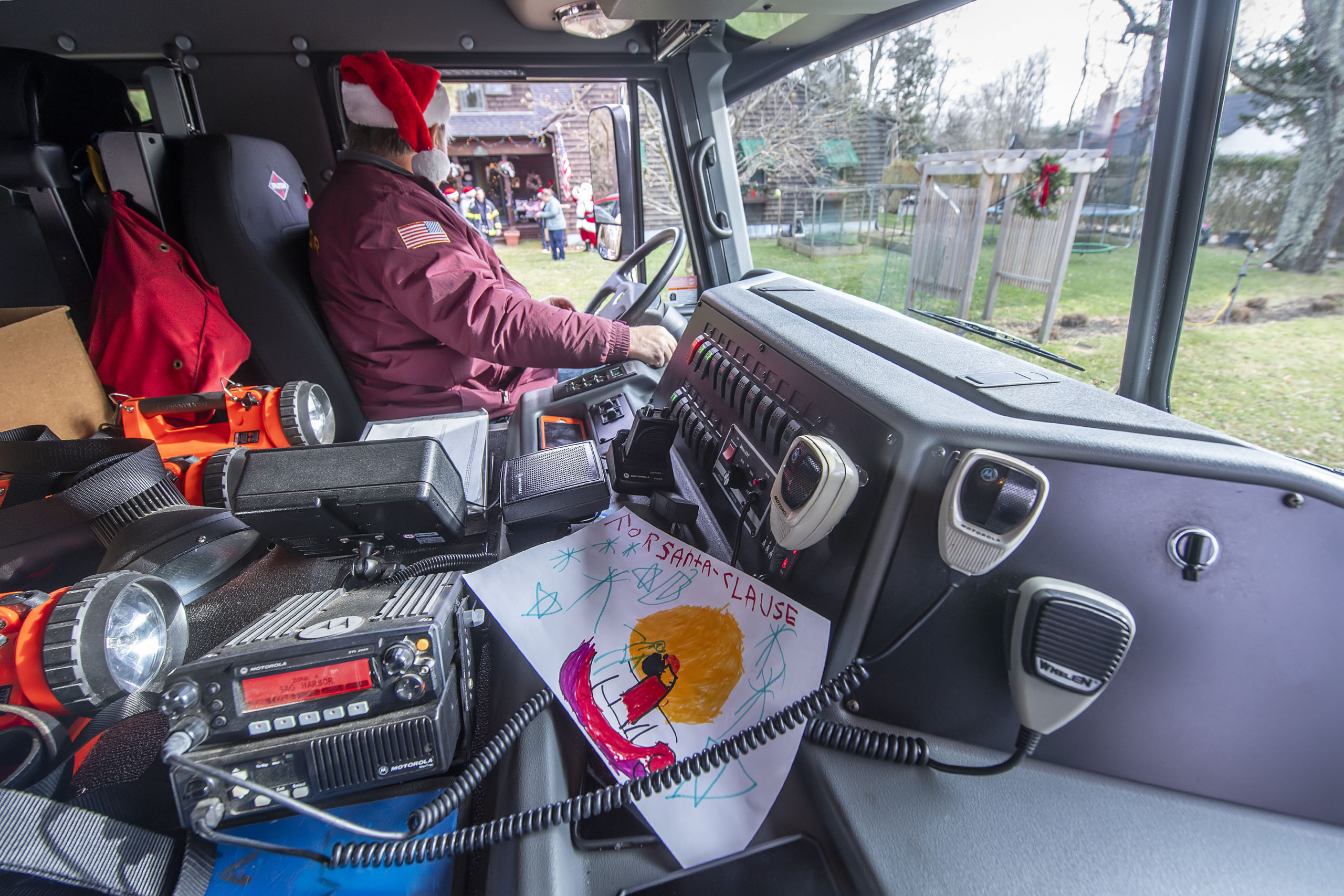 Firefighter Bruce Stafford waits in the truck as Santa Claus paid a visit to the good little boys and girls of North Haven, courtesy of the Sag Harbor Fire Department's Otter Hose Company on Saturday.