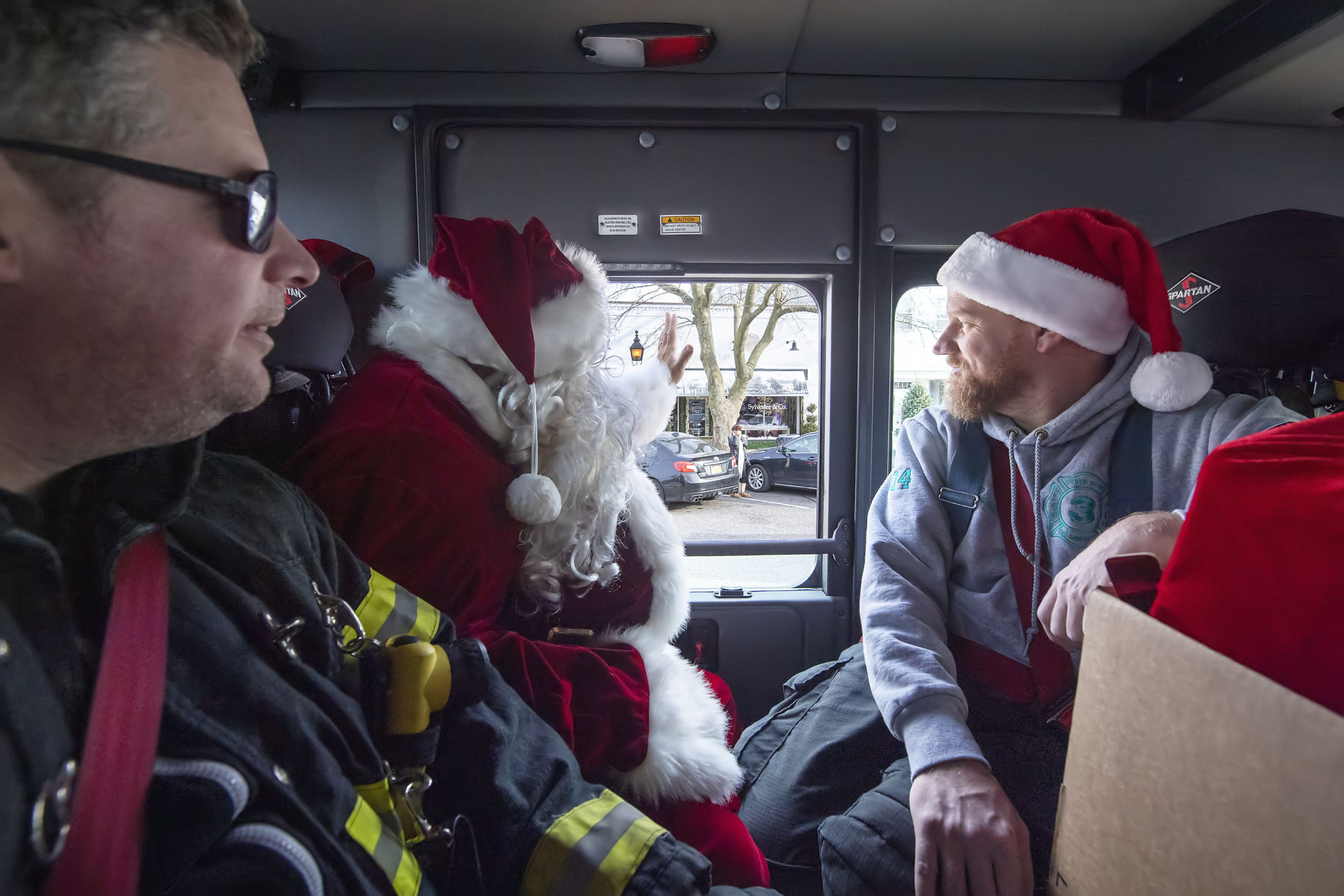 Santa Claus waves to folks on Main Street as Firefighters Scott Smith and Mike McQuade look on after Santa paid a visit to the good little boys and girls of North Haven, courtesy of the Sag Harbor Fire Department's Otter Hose Company, on Saturday.