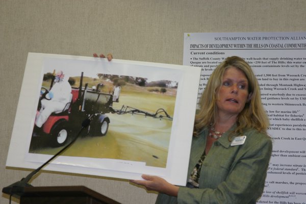 Colleen Carini displays a photo purported to be of a grounds crew worker applying chemical pesticides at Sebonack Golf Club. MRW