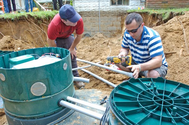 Crews work to finish up the new septic system at the Flanders home of Anthony Hobson on Thursday