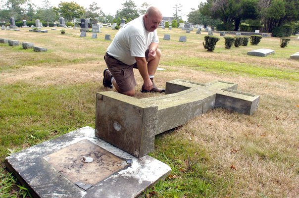 Southampton Cemetery Superintendent Eric Wright examines the damage to headstones by vandals in the cemetery on Wednesday.  DANA SHAW