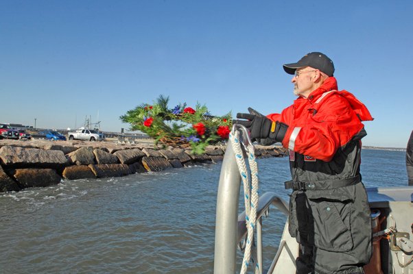 John Ryan tosses the memorial wreath into the inlet.