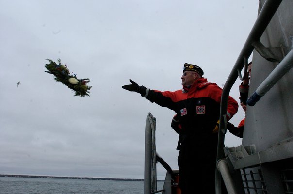 Hampton Bays American Legion member John Ryan tosses the memorial wreath in to the Shinnecock Inlet.