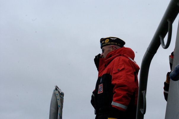 Hampton Bays American Legion member John Ryan tosses the memorial wreath in to the Shinnecock Inlet.