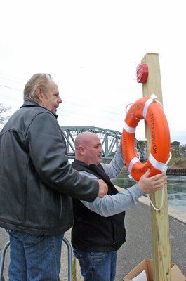 Southampton Rotary Club President Beau Hulse and Southampton Rotary member Robert Gill install life rings at the Shinnecock Canal on Thursday.