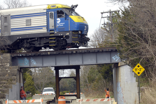 A train goes over the damaged bridge on Hill Station Road on Monday afternoon.