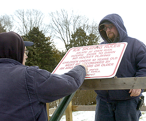 Southampton Village Parks Department employees Larry Wojcik and Steve Phillips put up a list of rules at the rink on Tuesday morning.