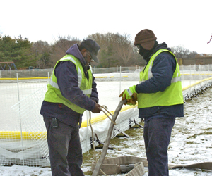 George Seymore and  Vincent Brumsey prepare to add more water to the rink.