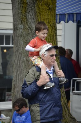 Three-year-old Chase Miller gets a good seat on Michael Miller for the Southampton Village Memorial Day Parade on Monday. BY ERIN MCKINLEY