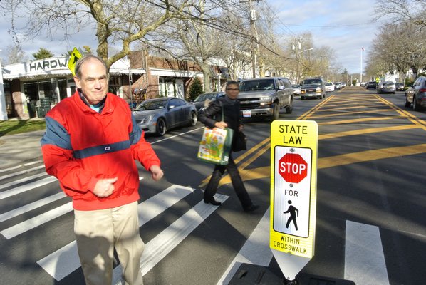 Dick Bruce places a pedestrian crossing sign near Thayer's Harware in Bridgehampton on Thursday afternoon. He also placed one in the crosswalk at the Bridgehampton Post Office.  DANA SHAW