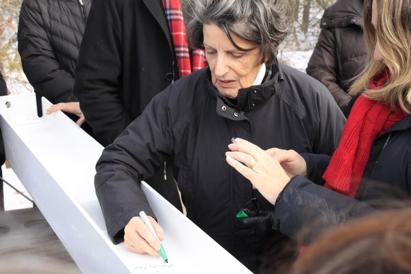 East End Hospice President and CEO Priscilla Ruffin signs the final beam that will be used to build the Kanas Center for Hospice Care on Tuesday morning in the parking lot of the East End Hospice office on Old Riverhead Road. KYLE CAMPBELL