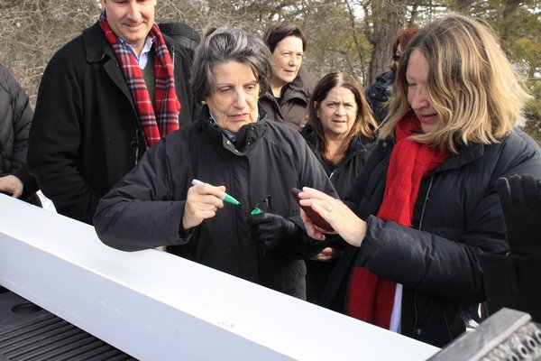 East End Hospice President and CEO Priscilla Ruffin signs the final beam that will be used to build the Kanas Center for Hospice Care on Tuesday morning in the parking lot of the East End Hospice office on Old Riverhead Road. KYLE CAMPBELL